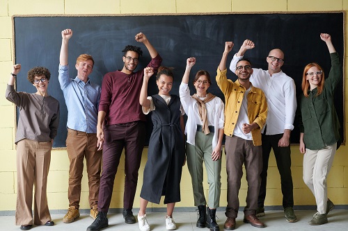 Diverse group of people cheering in front of a blackboard